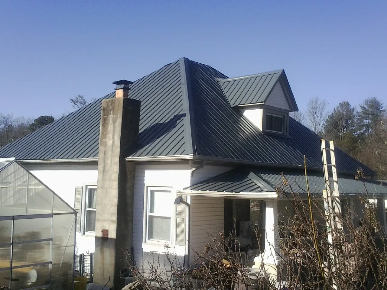 Dark blue standing seam metal roof on a white farmhouse with dormer — Slate & Tile Roof Repair by Roofing Brothers in Hasbrouck Heights