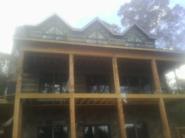 Dormers and porch framing on a large log home under construction — Roof Coating work by our crew in Hasbrouck Heights