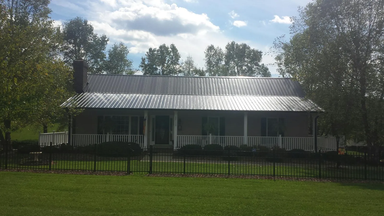 Gray metal roof on a brick ranch with a full width front porch — Gutter Guard Installation work by our crew in Hasbrouck Heights