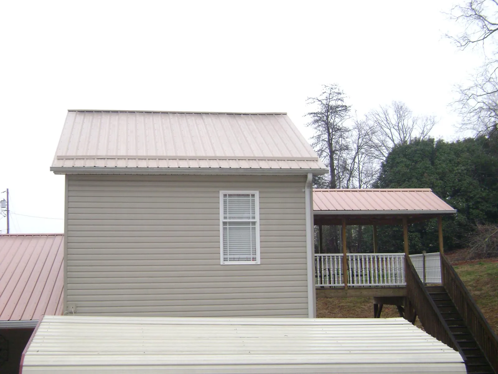 Tan metal roofs on a two story addition and attached porch, from a Roof Replacement job in Hasbrouck Heights