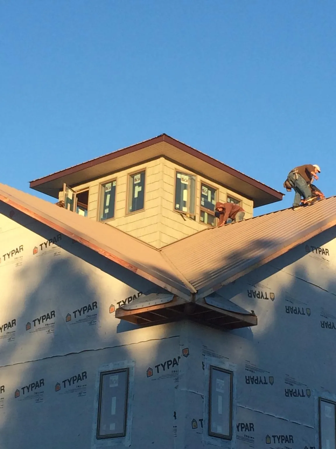 Roofers working around a rooftop cupola on a new metal roof at sunset — Roof Waterproofing in Hasbrouck Heights by Roofing Brothers